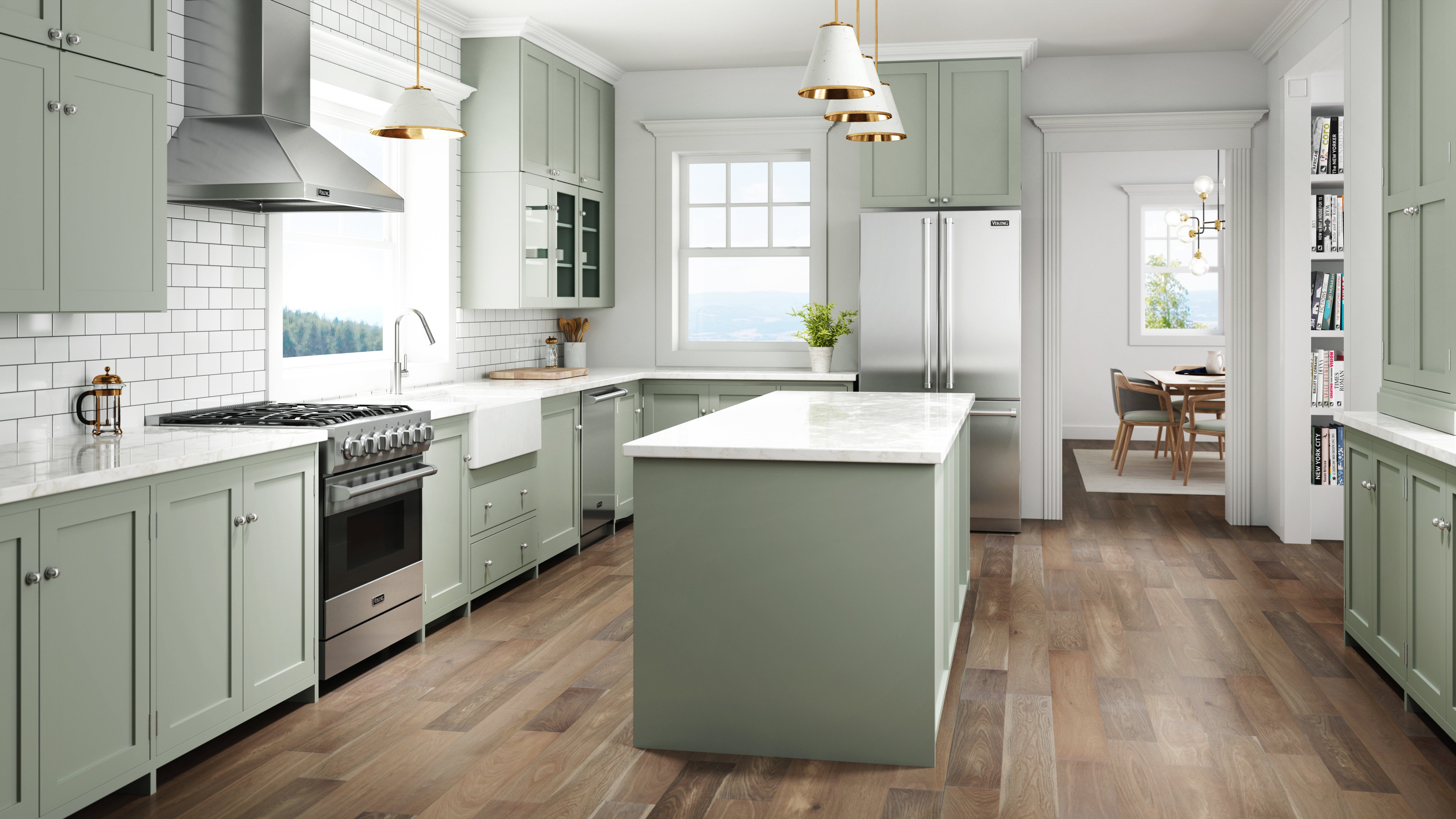 Modern kitchen with sage green cabinets, white marble countertops, stainless steel appliances, a large island, wood flooring, and pendant lights. There is a dining area visible through a doorway in the background.