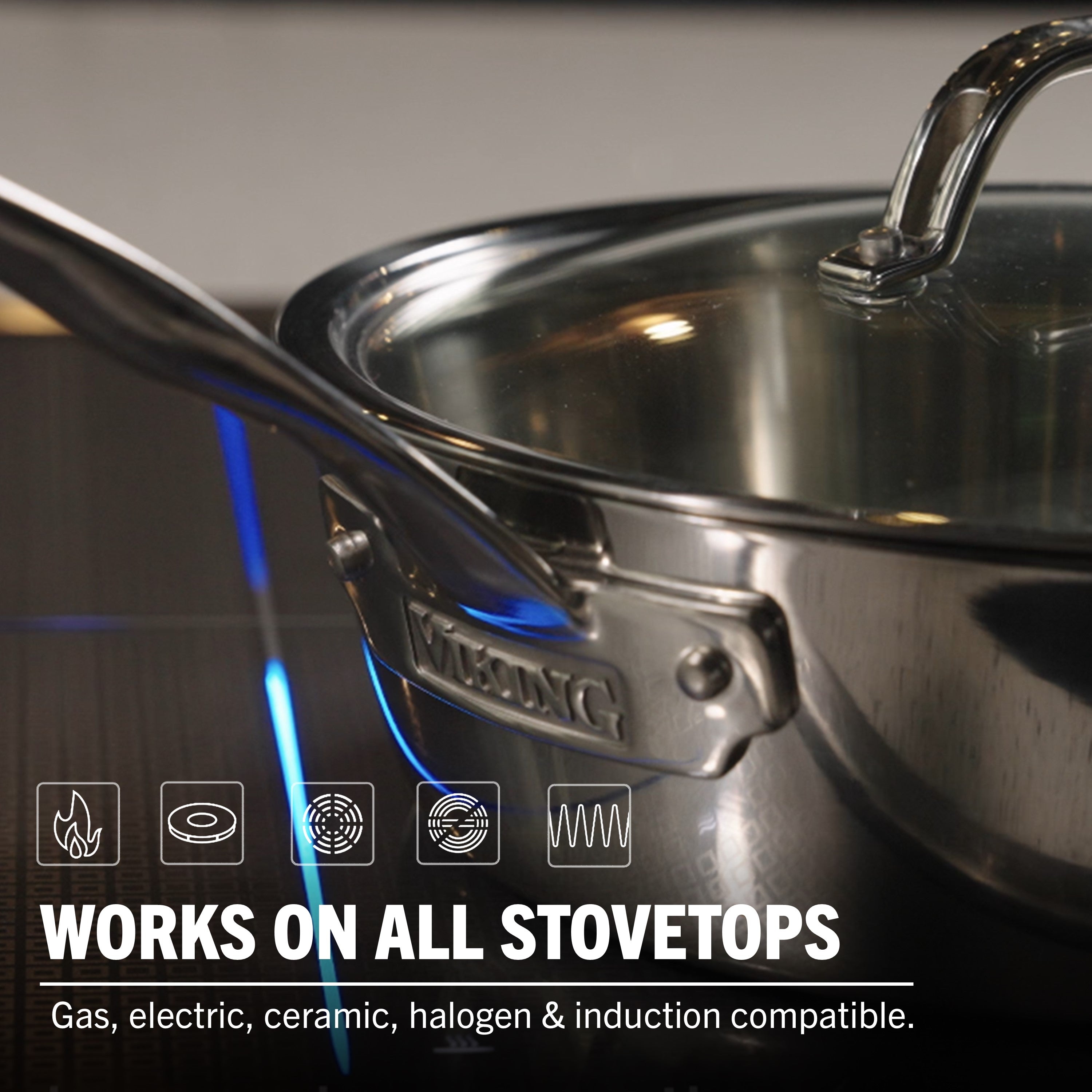 A close-up shows the Viking Contemporary 3-Ply 4.8-Quart Sauté Pan with Glass Lid by Viking Culinary Products on a stovetop, highlighted as stainless steel and induction compatible—ideal for gas, electric, ceramic, halogen, and induction cooktops.