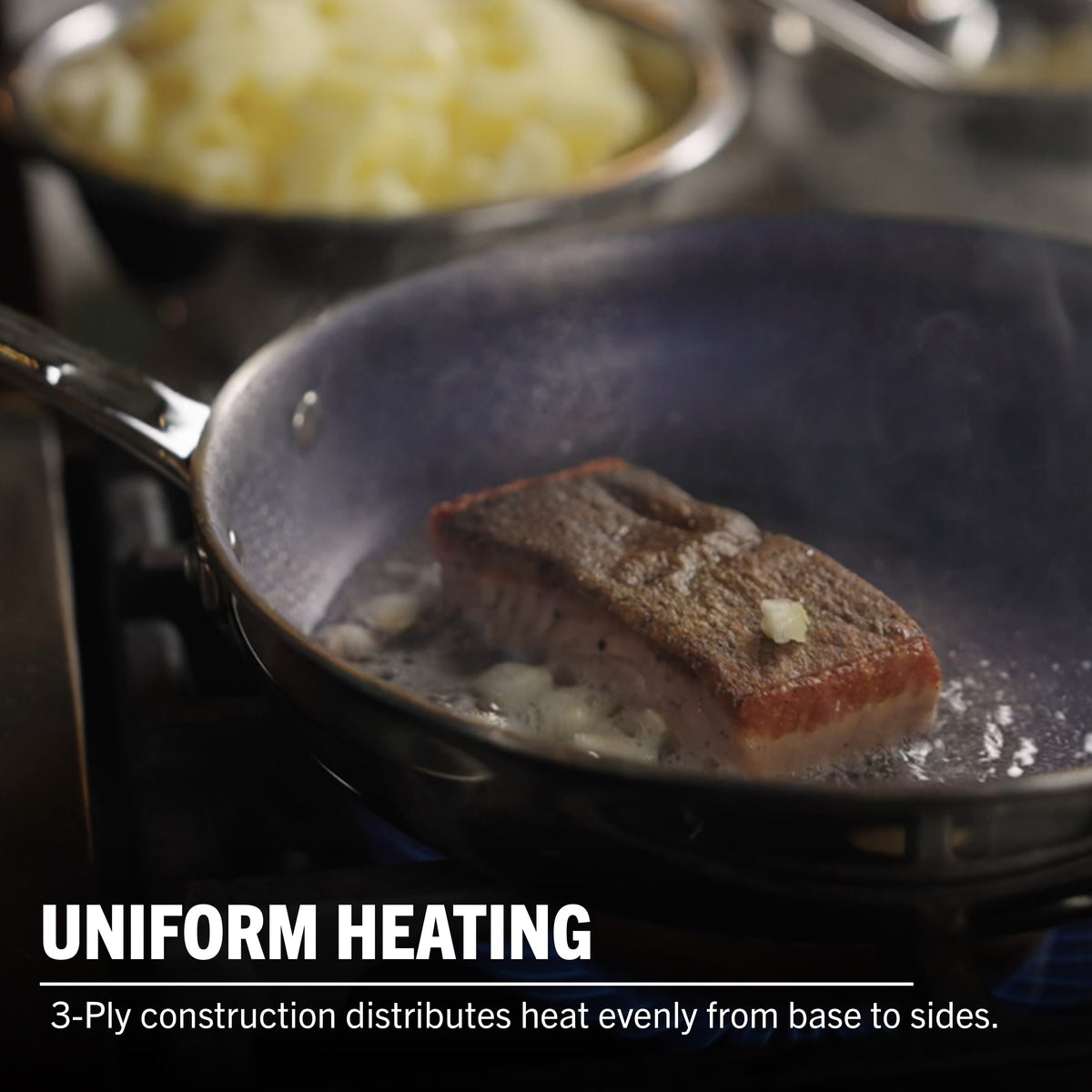 A piece of salmon cooks in the Viking 3-Ply Hybrid Plus Ceramic 8-inch Nonstick Fry Pan by Viking Culinary Products, with steam rising and diced onions nearby. Text: UNIFORM HEATING. 3-ply design ensures even heat distribution and works on induction cooktops.