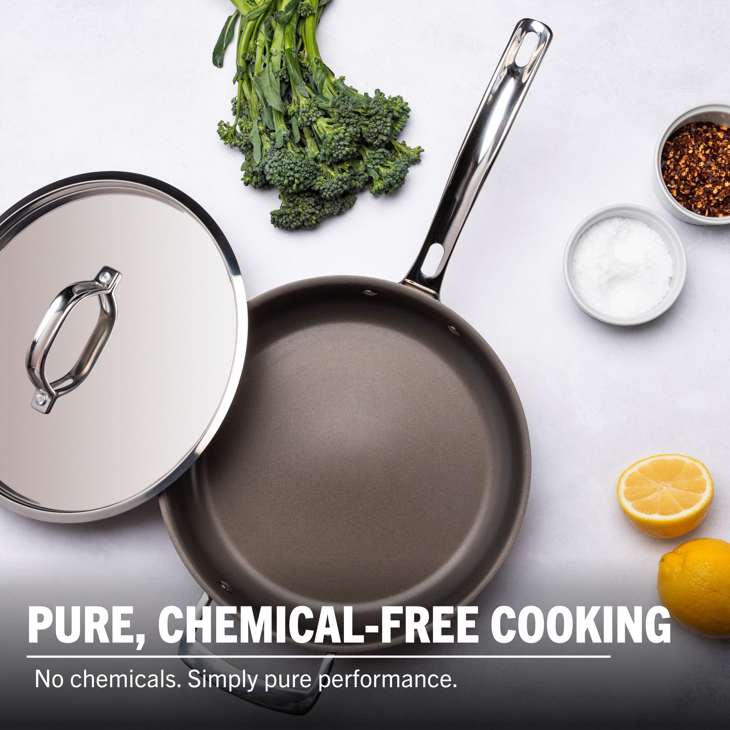 The Viking PureGlide Pro 3-Ply 4.5-Quart Saute Pan with Metal Lid rests on a white surface with broccolini, lemon, salt, and red pepper flakes. PURE, CHEMICAL-FREE COOKING from Viking Culinary Products: No chemicals—simply pure cookware performance.