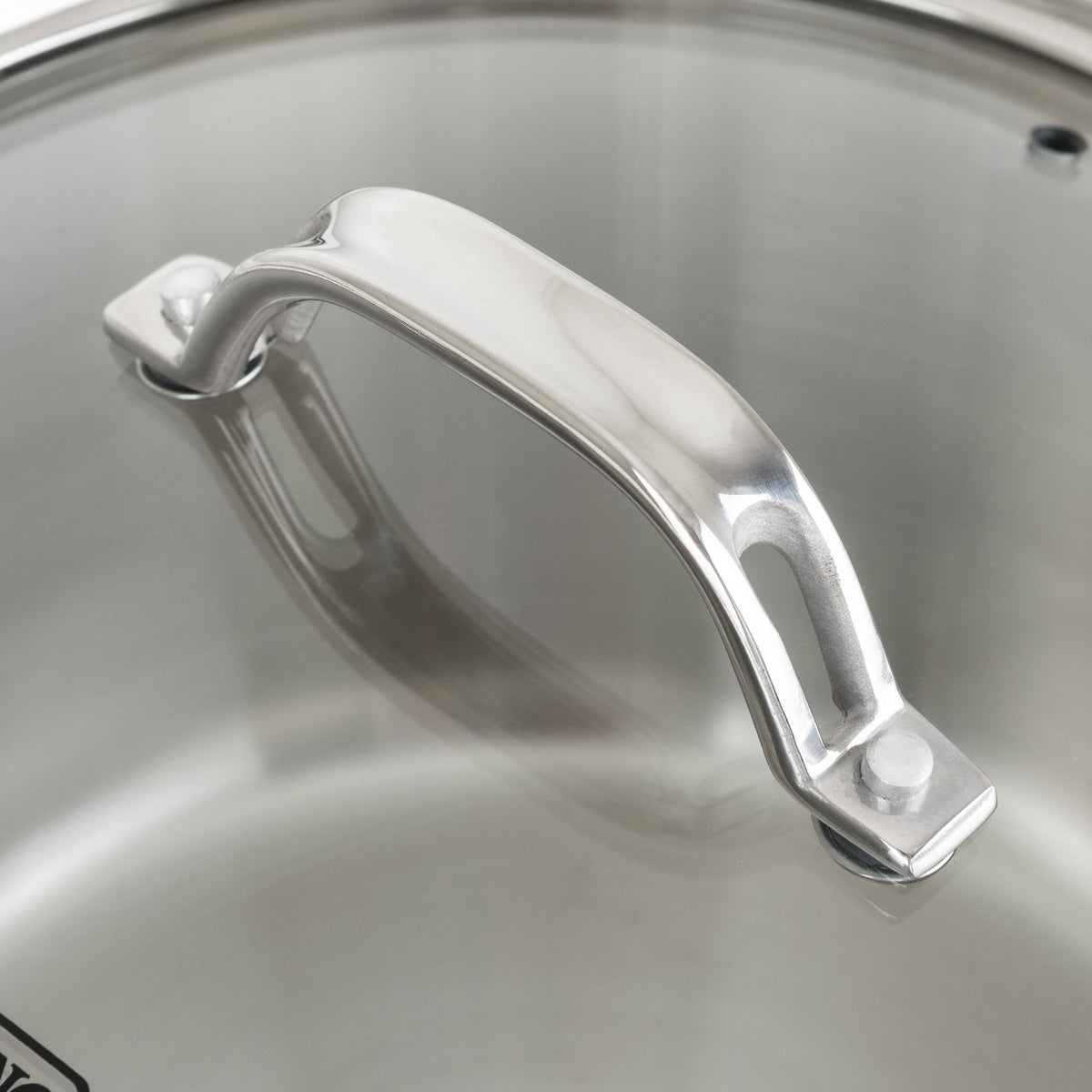 Close-up of a polished stainless steel handle on the glass lid of a Viking Contemporary 3-Ply Stainless Steel Cookware Set by Viking Culinary Products, showing a clear reflection on the lid.