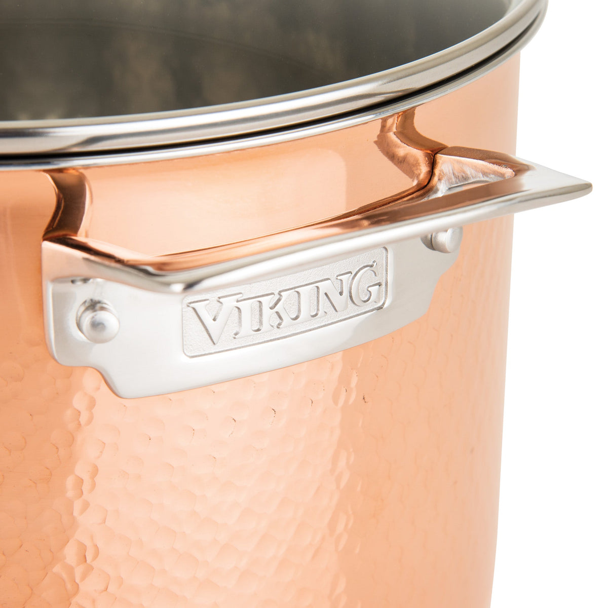 Close-up of a Viking Culinary Products 3-Ply Hammered Copper Clad pot with ergonomic handle and glass lid, showcasing its shiny, durable, and reflective surgical grade stainless steel construction. Part of the 10-piece cookware set.