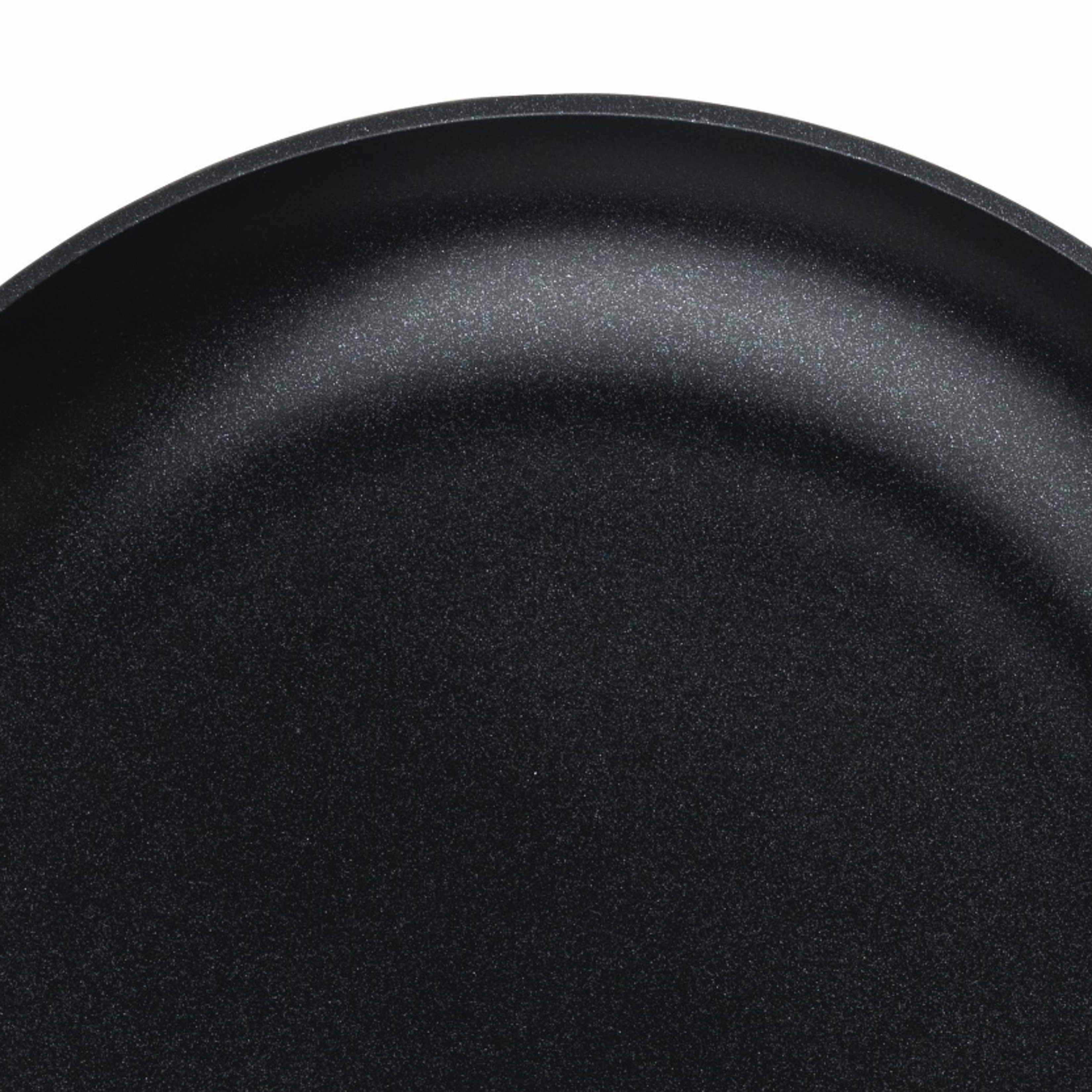 Close-up view of a black nonstick frying pan, showing its smooth, slightly textured cooking surface and curved edge against a white background.