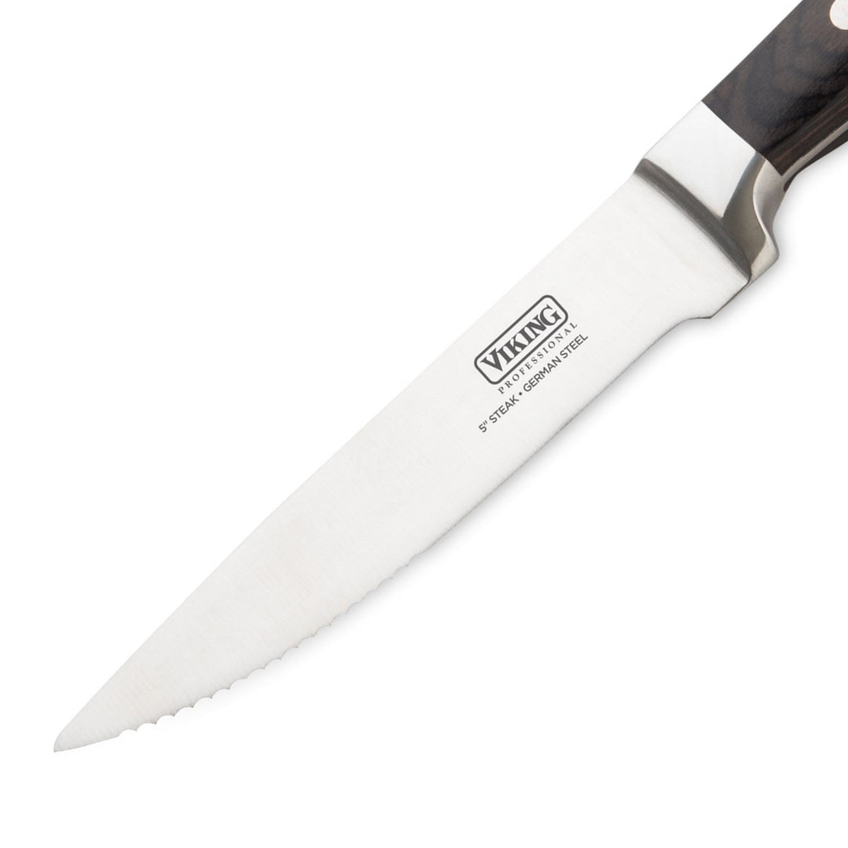 A close-up of a Viking brand steak knife with a stainless steel blade and a serrated edge, featuring a dark handle and the logo “Viking” visible on the blade.