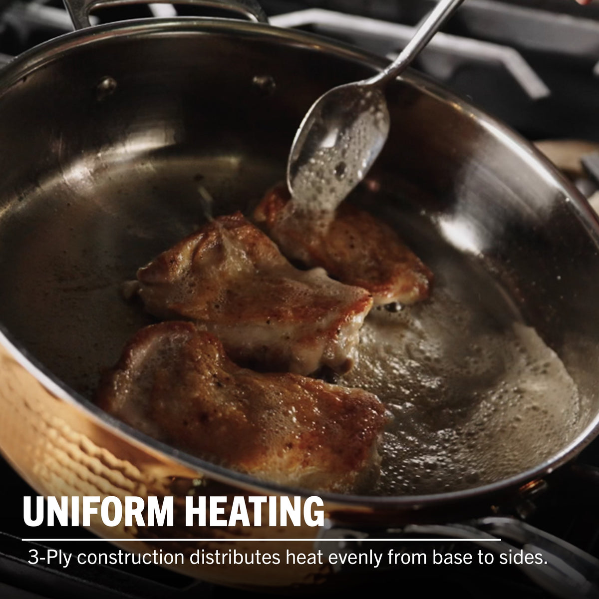 Chicken is being seared and basted in Viking Culinary Products’ 3-Ply Hammered Copper Clad Cookware. Uniform heating from the stainless steel interior ensures even cooking. Text: CONSISTENT HEAT. 3-Ply construction delivers optimal heat distribution.