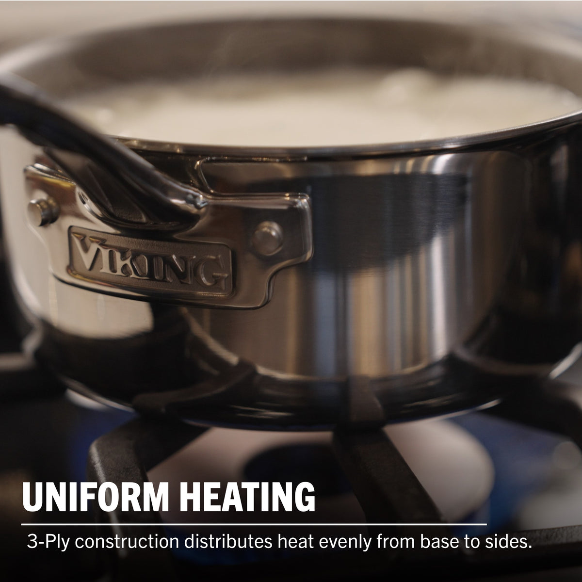 A Viking Culinary Products PureGlide Pro 3-Ply 3-Quart Sauce Pan with metal lid sits on a gas stove as liquid boils. Text: Uniform Heating—Tri-ply construction ensures even heat distribution from base to sides.