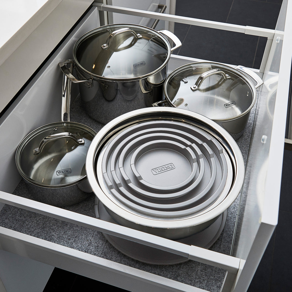 Open kitchen drawer with three stainless steel pots with lids on the left and back, and a Viking 10-Piece Stainless Steel Mixing Bowl Set with Lids by Viking Culinary Products neatly organized on the right.