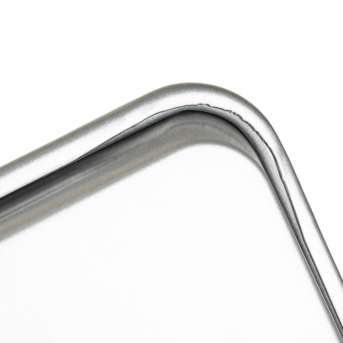 Close-up of a rounded metal corner with a shiny, silver finish and visible seam on the Viking 2-Piece Nonstick Aluminized Steel Baking Sheet Set by Viking Culinary Products, featuring a smooth, reflective surface for excellent heat conductivity.