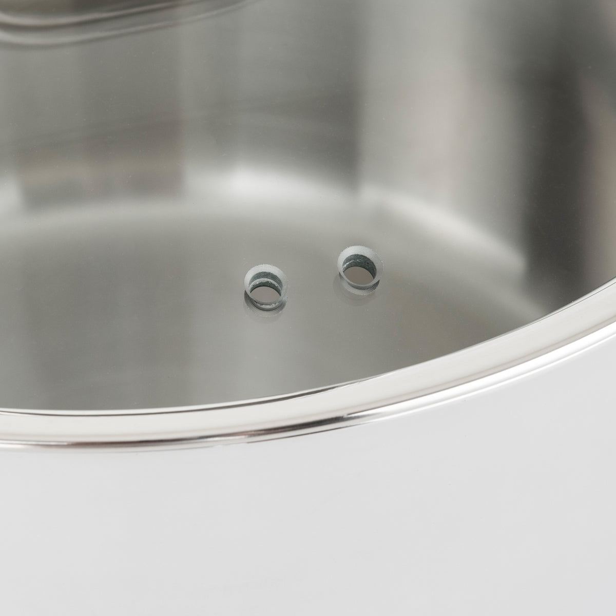 A close-up of the Viking Contemporary 3-Ply 3.6-Quart Sauté Pan with Glass Lid from Viking Culinary Products, featuring two small steam vent holes and a shiny rim, ideal for induction compatible cooking.