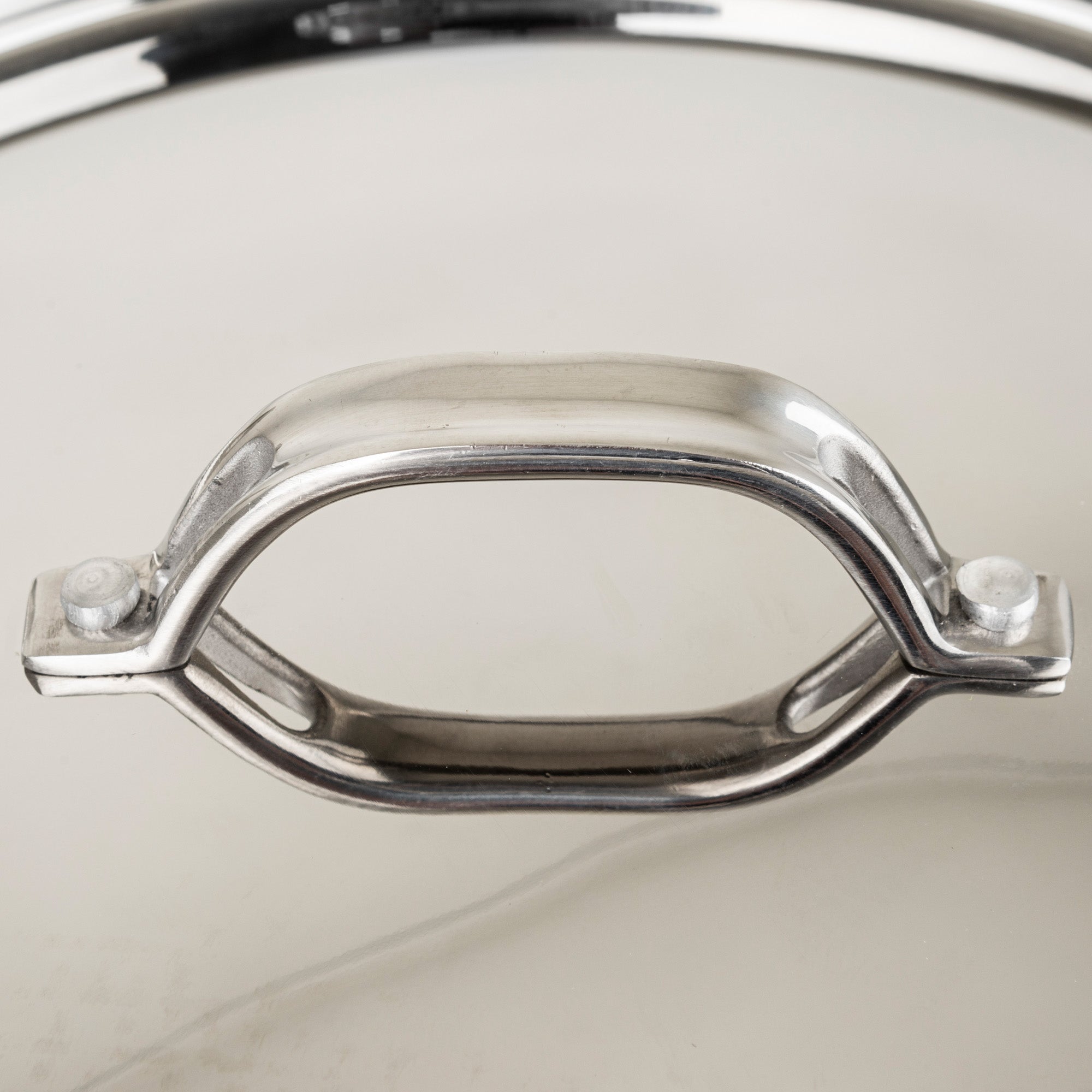 Close-up of the shiny metal handle on a Viking Culinary Products Viking Contemporary 4-Ply Copper Clad 9-Piece Cookware Set lid, highlighting reflections and the smooth stainless steel surface suitable for induction cooking.