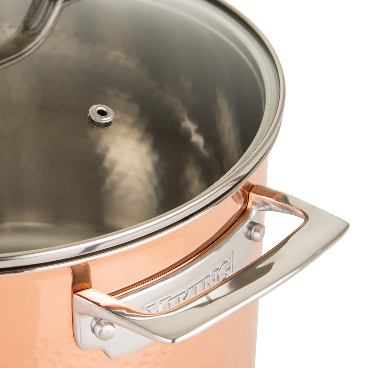 Close-up of a Viking Culinary Products 3-Ply Hammered Copper Clad saucepan, featuring an ergonomic handle and glass lid with steam vent. The reflective, textured surface showcases durable hammered copper with elegant metal accents.
